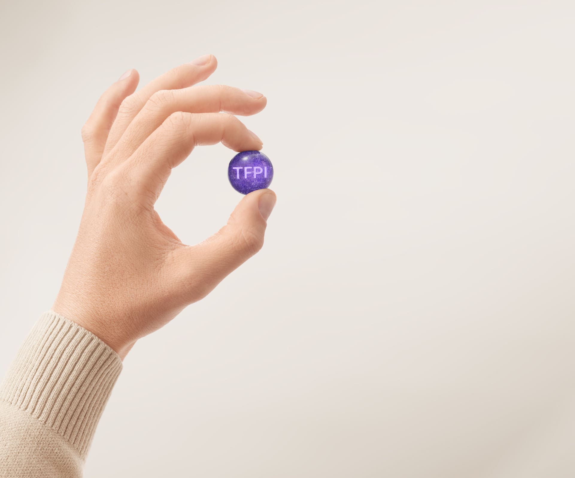 A hand holding a small purple ball representing TFPI